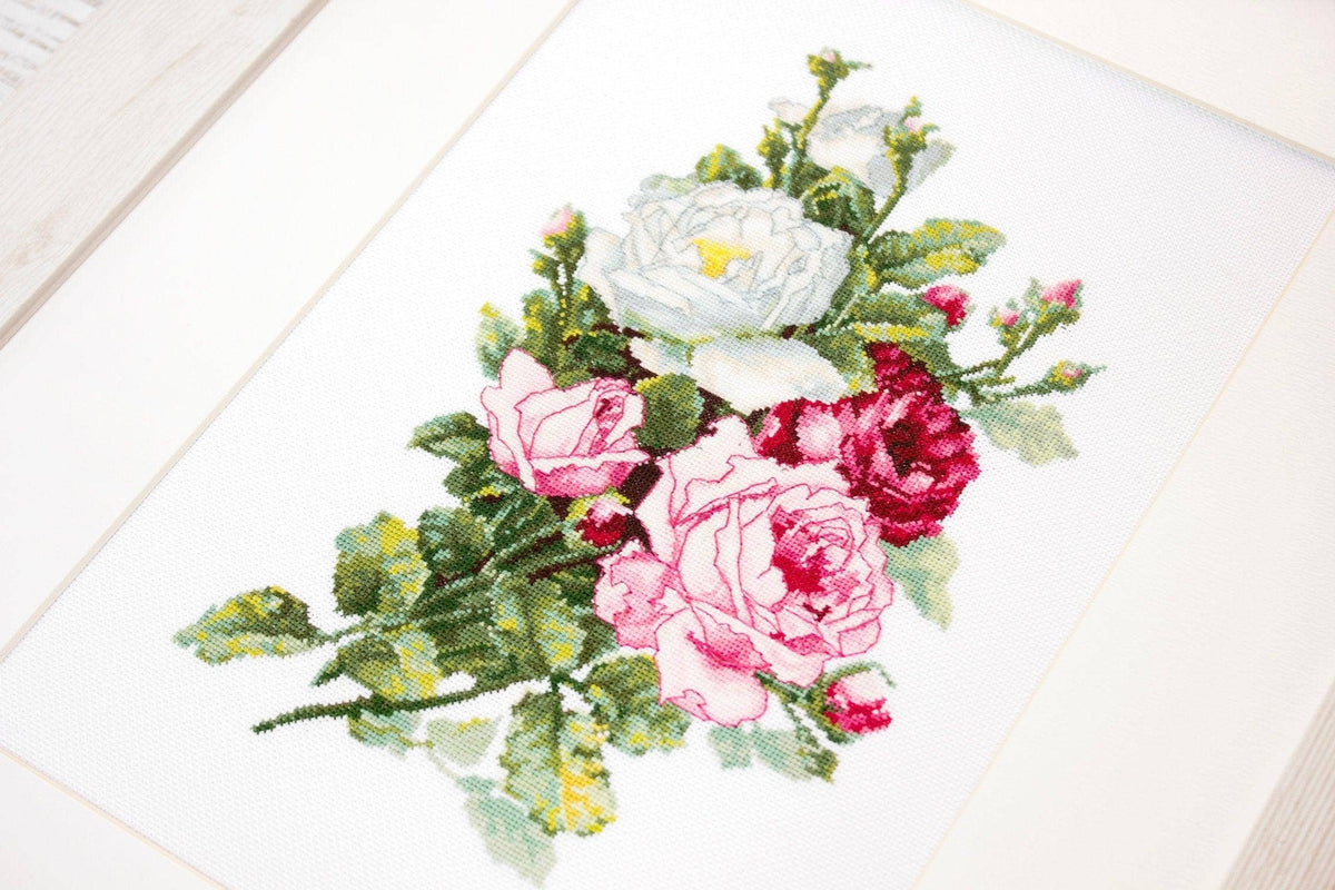 Cross-stitched floral design on fabric with a white wooden surface underneath