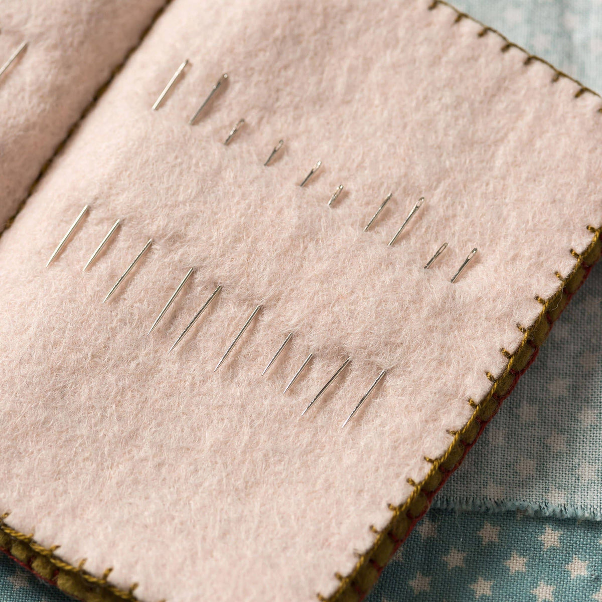 Needles on a pink fabric with a green border